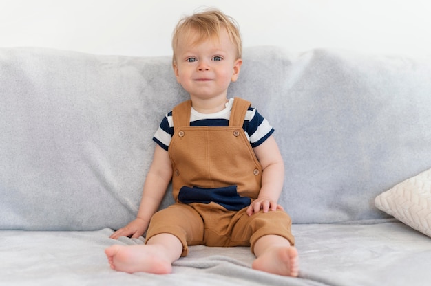 Foto gratuita bambino sveglio del colpo pieno che si siede sul divano