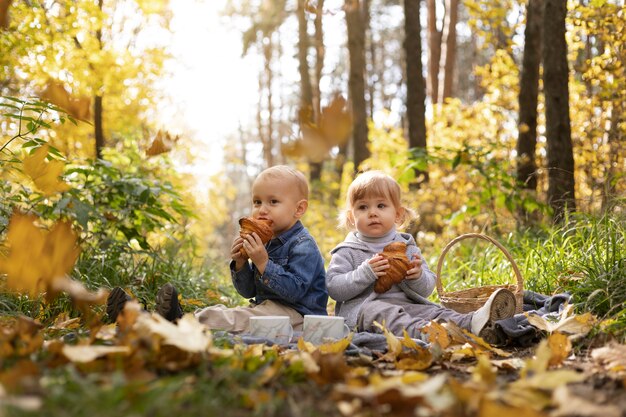 自然の中で座っているフルショットかわいい子供たち