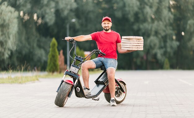 Full shot delivery guy on motorcycle with order