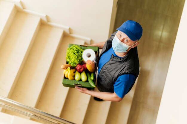 Free photo full shot delivery man holding food crate