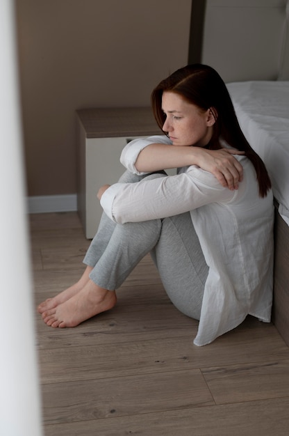 Full shot depressed woman on floor