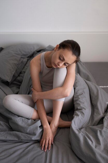 Full shot depressed woman with blanket