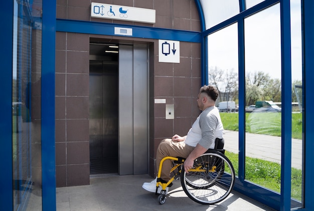 Uomo disabile a tutto campo che prende l'ascensore