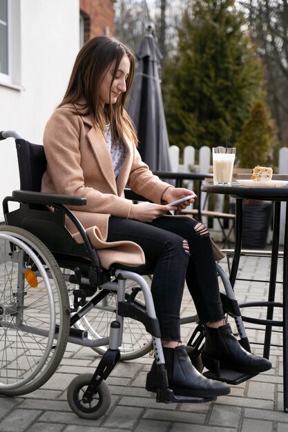 Full shot disabled woman holding smartphone