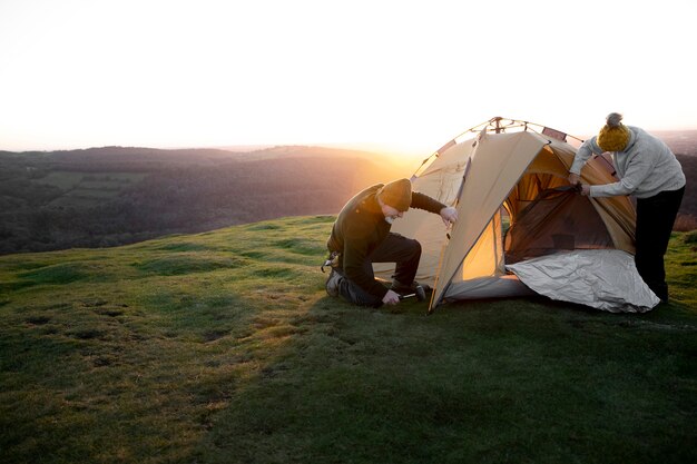 Full shot explorers setting up tent