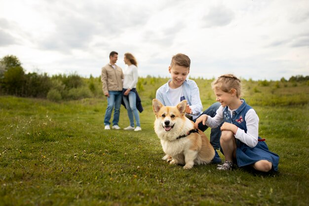 Full shot family playing with dog outdoors