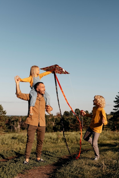 Бесплатное фото Полная семья, играющая с воздушным змеем