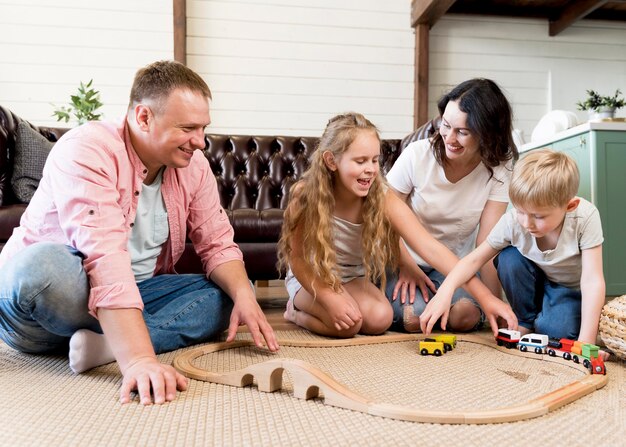 Full shot family playing with train