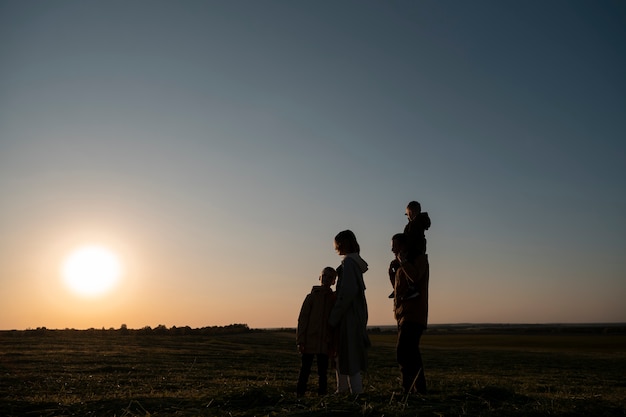 Siluetta della famiglia del colpo pieno che si diverte al tramonto