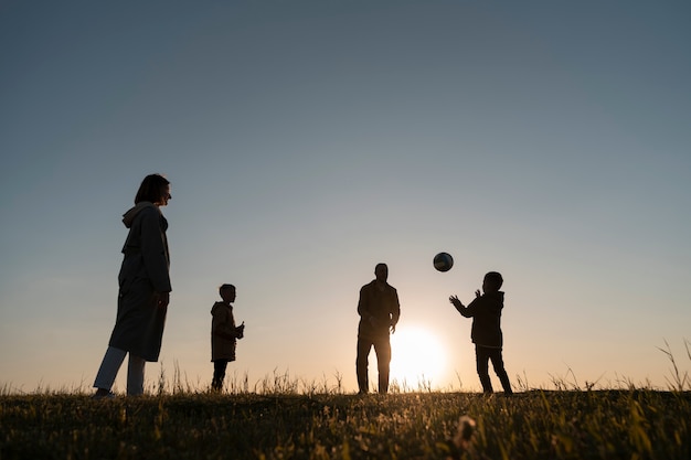 Foto gratuita siluetta della famiglia del colpo pieno che si diverte al tramonto