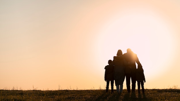 Foto gratuita siluetta della famiglia del colpo pieno che si diverte al tramonto