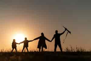 Free photo full shot family silhouette having fun at sunset