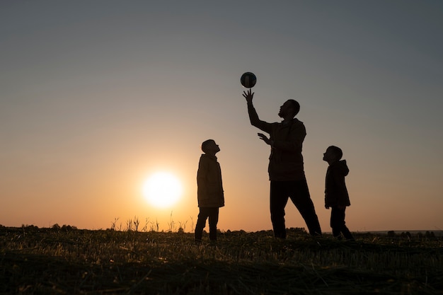 Free photo full shot family silhouette having fun at sunset