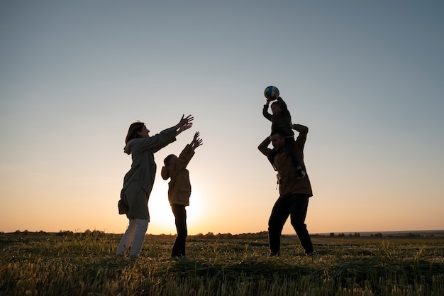 Free photo full shot family silhouette having fun at sunset