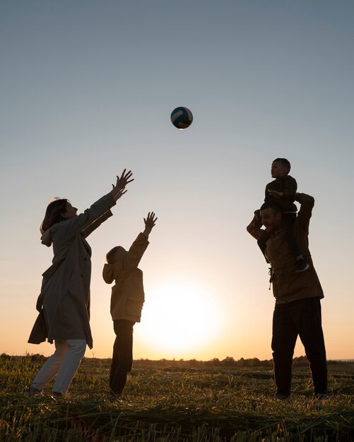 Foto gratuita siluetta della famiglia del colpo pieno che si diverte al tramonto