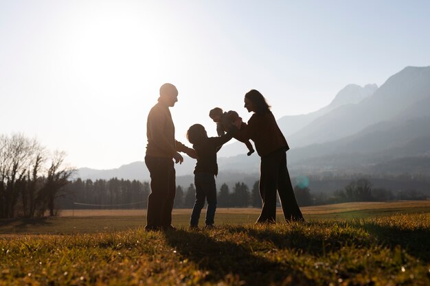 Siluetta della famiglia del colpo pieno in natura al tramonto