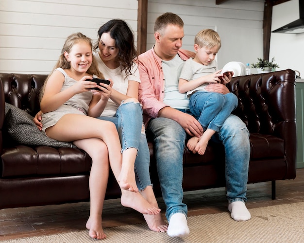 Famiglia della foto a figura intera che si siede sullo strato