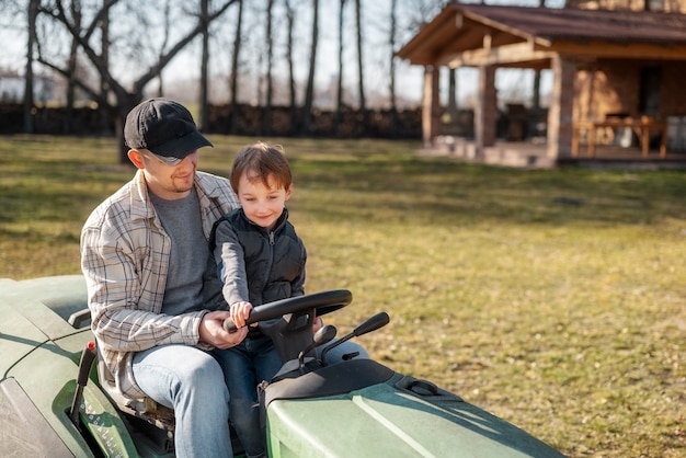 Full shot father driving lawn mower