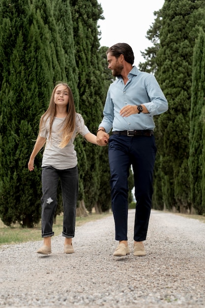 Full shot father and girl holding hands