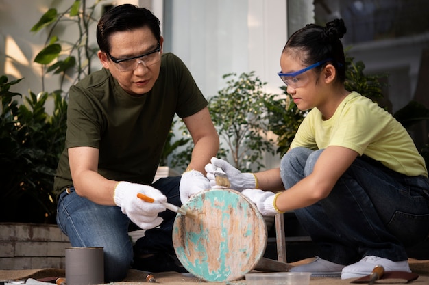 Full shot father and girl scrubbing wooden chair