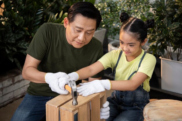 Full shot father and girl using hammer