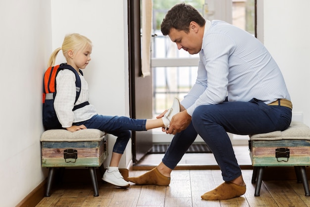 Free photo full shot father helping kid put her shoes on