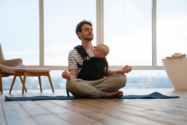 Free photo full shot father holding baby while meditating