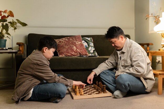 Full shot father and kid playing chess