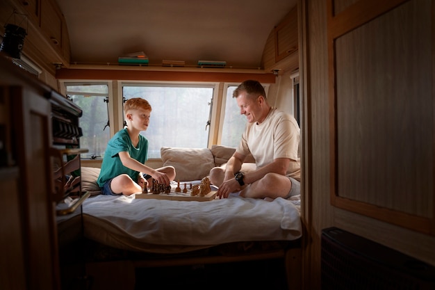 Free photo full shot father and kid playing chess