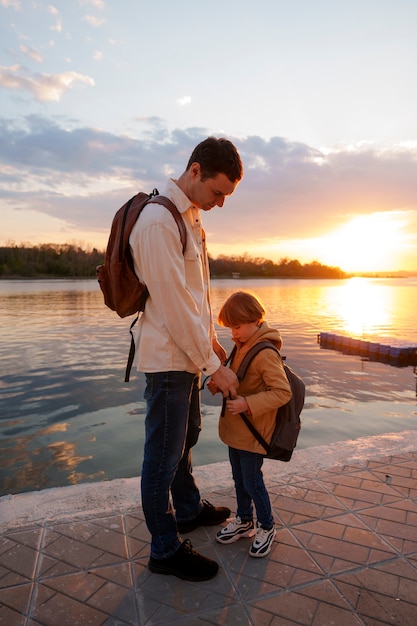 Foto gratuita padre e figlio a figura intera che bazzicano su un molo