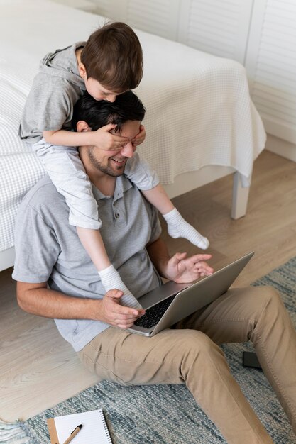 Full shot father working on floor with kid