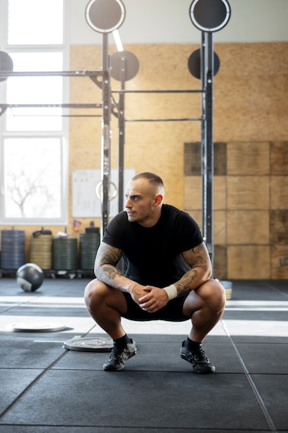 Foto gratuita uomo in forma a tutto campo seduto in palestra