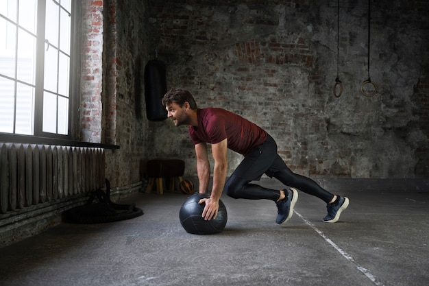 Free photo full shot fit man training with gym ball