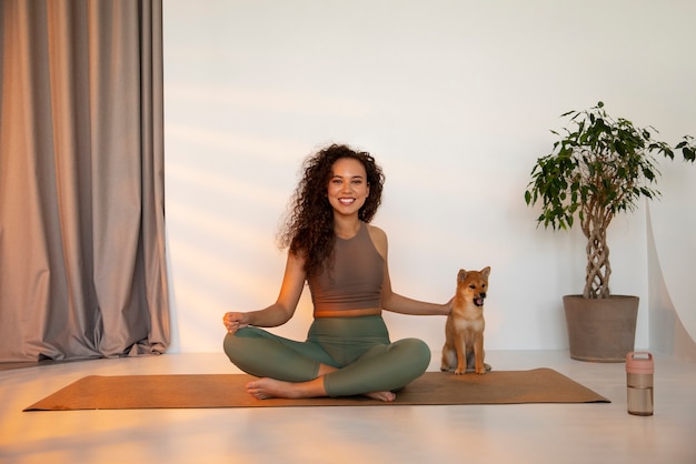 Free photo full shot fit woman doing sport with dog indoors