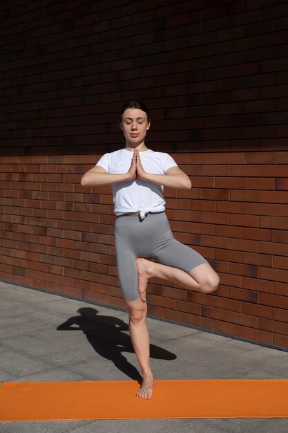 Full shot fit woman doing yoga on mat