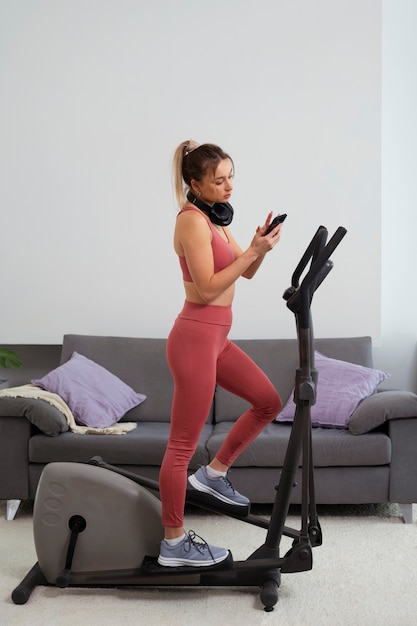 Free photo full shot fit woman on exercise bike