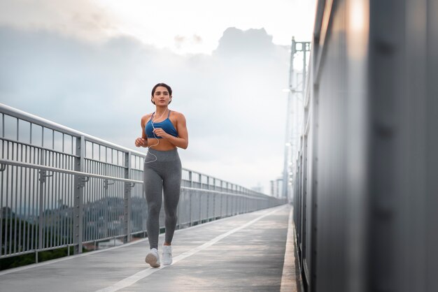 Full shot fit woman running outdoors