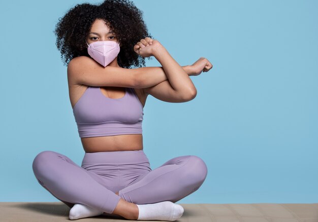 Full shot fit woman stretching with mask