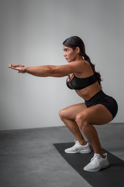 Free photo full shot fit woman training indoors