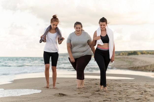 Full shot fitness friends walking on shore