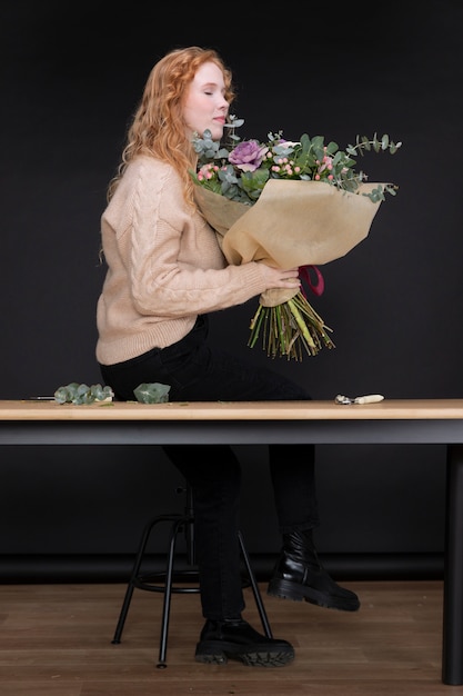 Free photo full shot florist holding bouquet