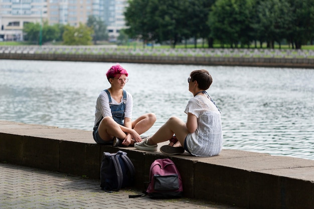 Free photo full shot friends chatting near river