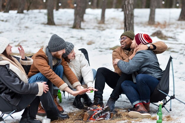 Full shot friends getting warm by the fire