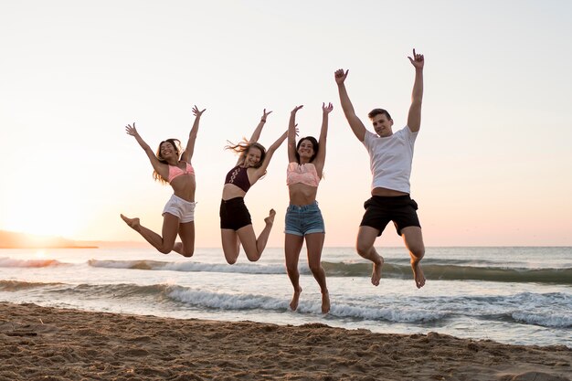 Full shot friends jumping on beach