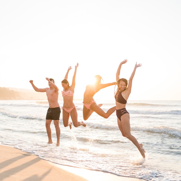 Full shot friends jumping on beach