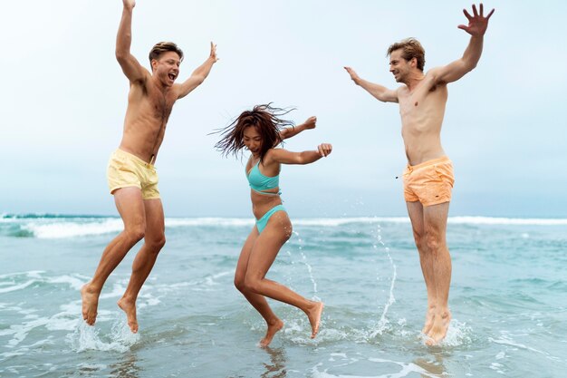 full shot friends jumping in sea