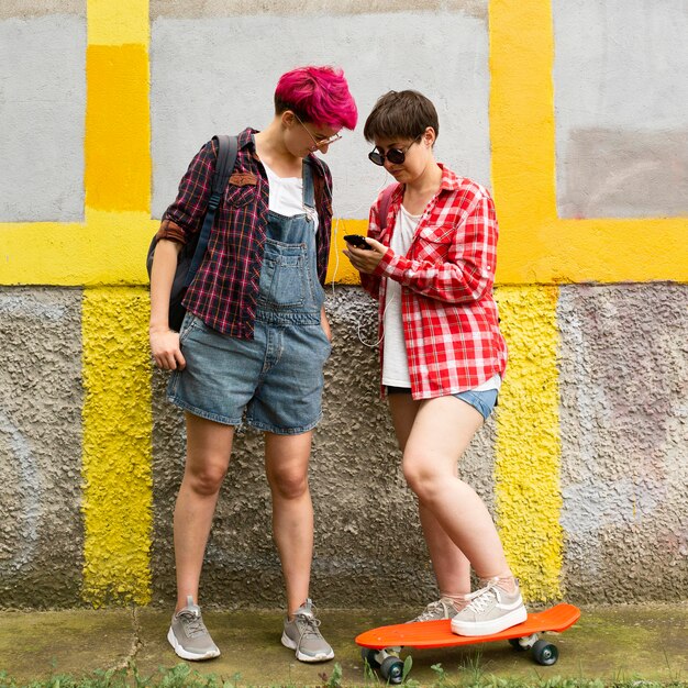 Full shot friends looking at smartphone