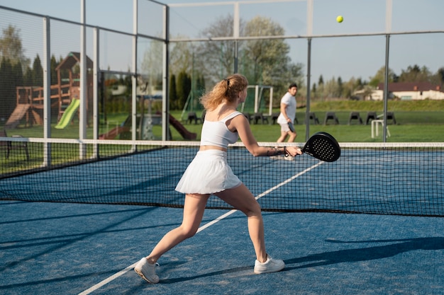 Полный снимок друзей, играющих в паддл-теннис на открытом воздухе