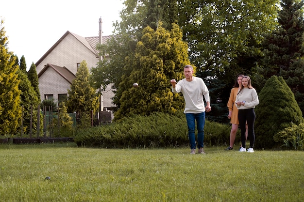 Full shot friends playing pétanque outdoors