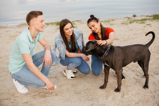 Full shot friends playing with beautiful dog